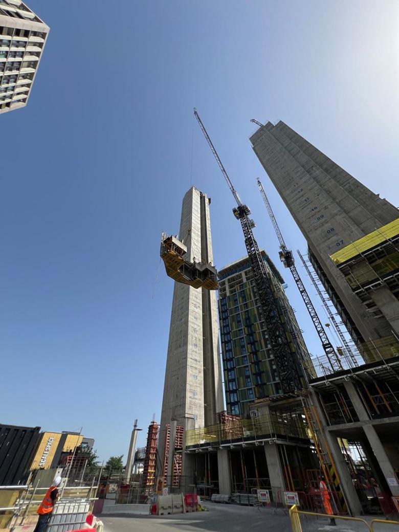 Tower crane lifting a climbing-form platform onto a concrete core